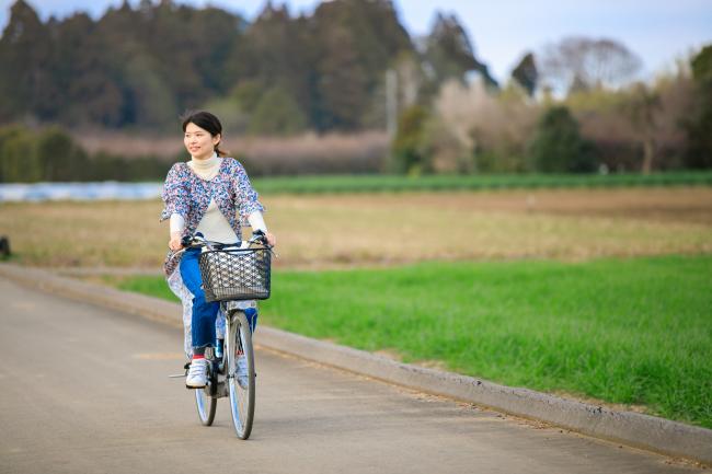 田畑風景を自転車で走っている女性の写真