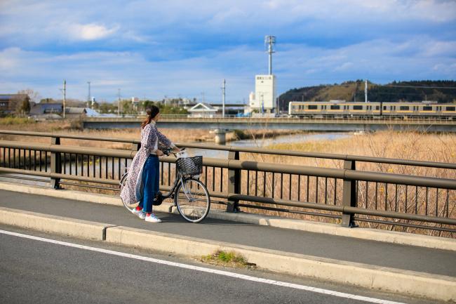栗山橋から電車を見ている女性の写真